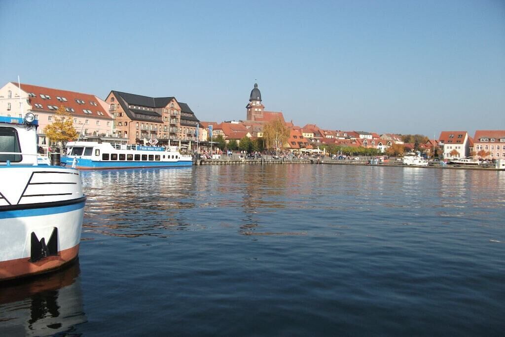A river with boats, buildings, and a tower in the background.