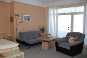 A living room with a sofa, armchair, coffee table, and a bed. - Holiday apartment with 1 bedroom (Waren (Müritz))