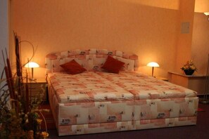 Ein Einzelbett mit einem gemusterten Kopfteil und zwei Nachttischlampen.