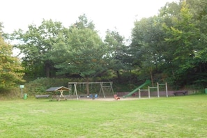 A park with a swing set, a slide, and a picnic area. - Holiday apartment in Seedorf with barbecue (Seedorf)