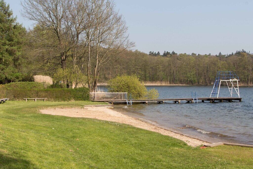 A lakeside park with a wooden dock, a grassy area, and trees.