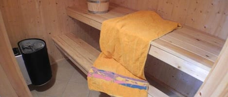 A sauna with wooden benches and a bench with a yellow towel.
