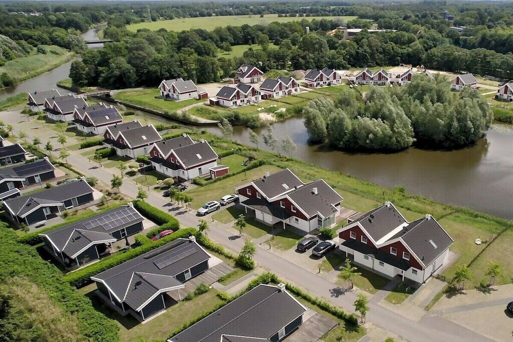 Un quartier résidentiel où les maisons sont alignées le long d’une rivière, avec un mélange de bâtiments à un ou deux étages, tous dotés de toits inclinés.