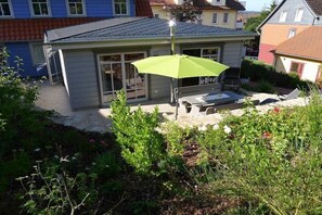 A residential property with a patio area, a green umbrella, and a small garden. - Bergmannstrost 5-star holiday apartment (Sankt Andreasberg)