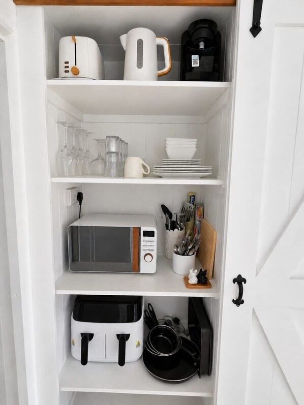 A white kitchen cabinet with various appliances and utensils.