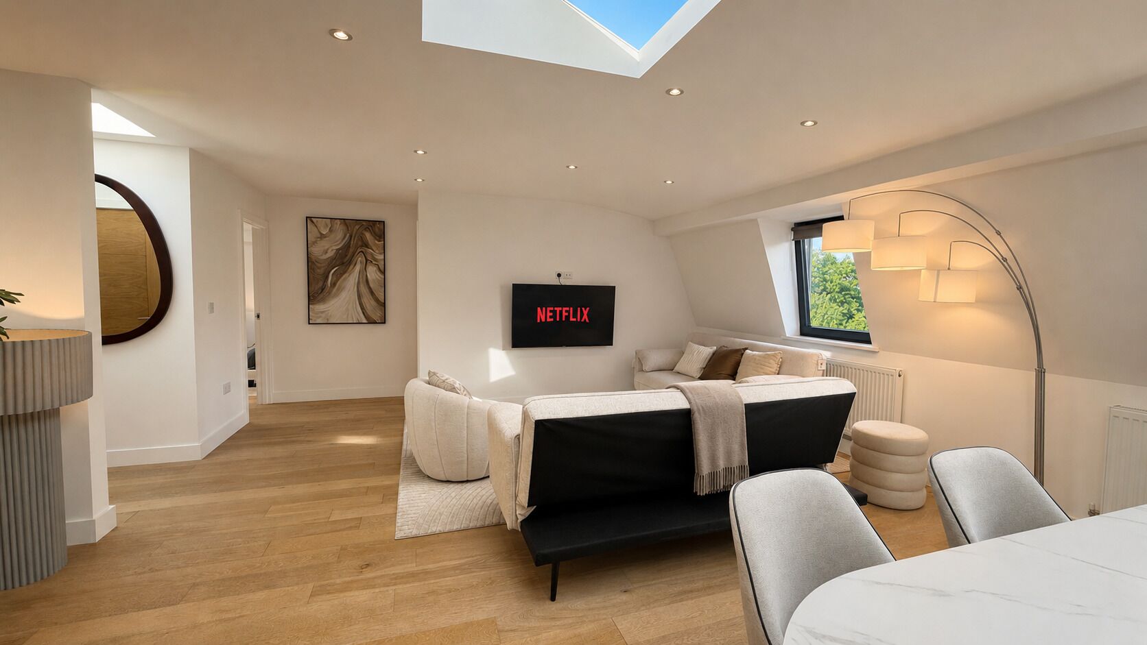 A modern bedroom with a bed, a TV mounted on the wall, and a skylight.