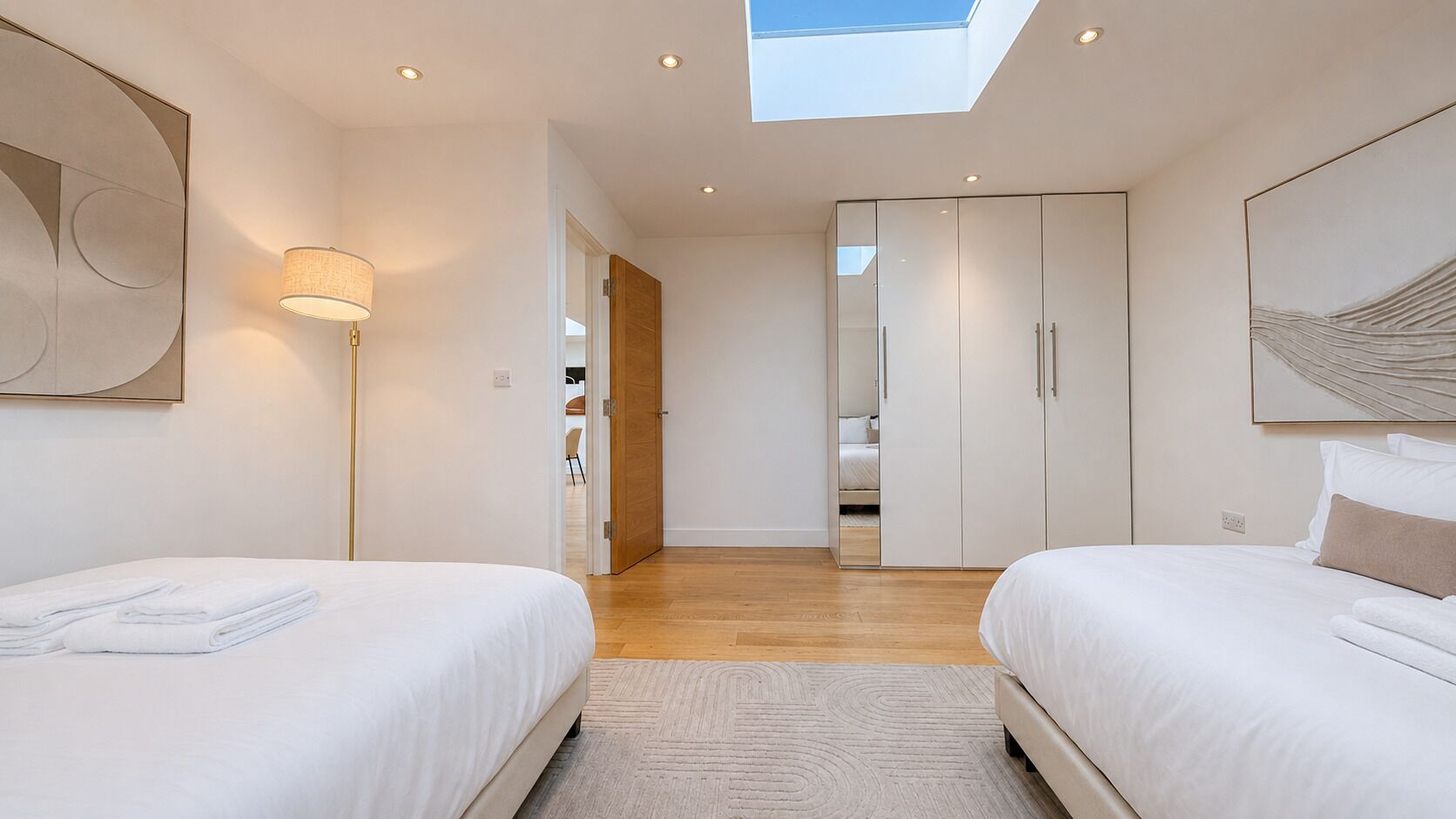 A modern bedroom with two beds, a skylight, and a walk-in closet.