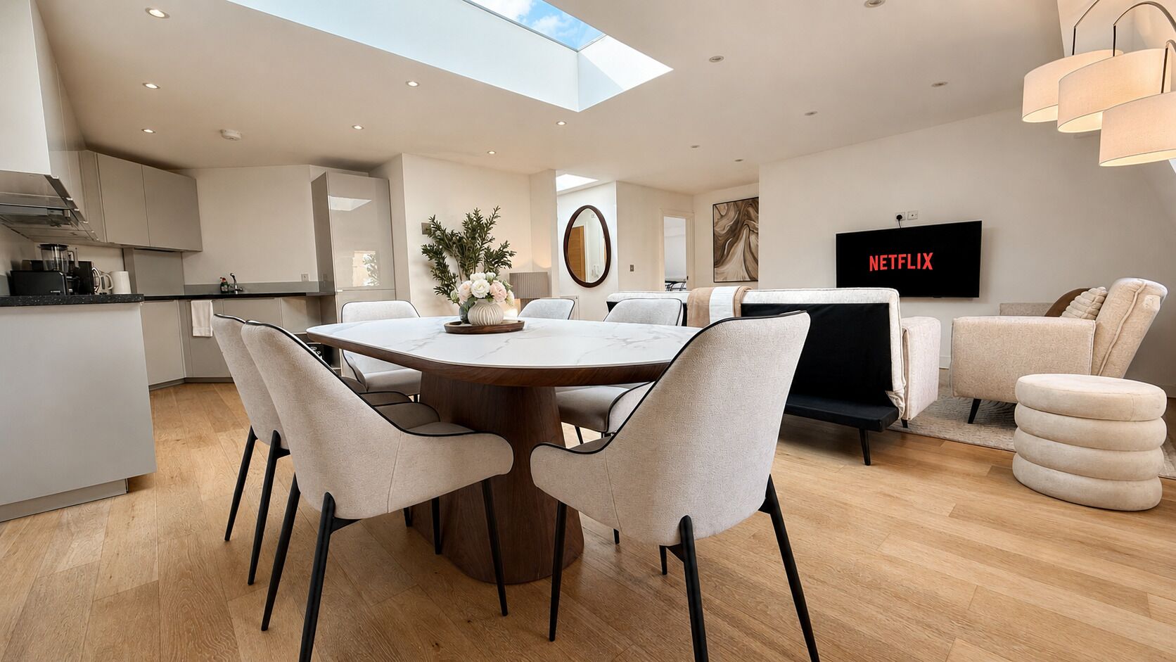 A modern living space with a dining area, kitchen, and seating area.