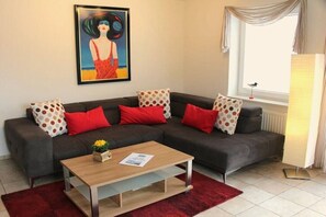 A modern living room with a sectional sofa, a wooden coffee table, and a painting on the wall. - HOUSE LUV 2 - on the ground floor (Wittdün)