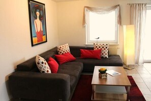 A living room with a sofa set, a coffee table, and a painting on the wall. - HOUSE LUV 2 - on the ground floor (Wittdün)