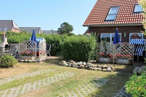A garden with a brick house, a barbecue grill, and a paved pathway. - HOUSE LUV 2 - on the ground floor (Wittdün)