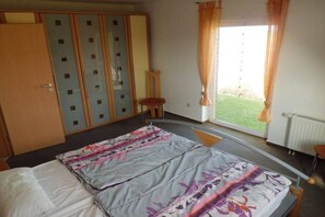 A bedroom with a bed, a wardrobe, a window with curtains, and a view of a lawn. - Holiday home in Dorum with swimming pool (Dorum)