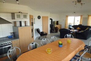 A modern kitchen with a dining area, a sofa, and a fireplace. - Holiday home in Dorum with swimming pool (Dorum)