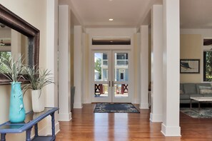 A hallway with a wooden floor, a staircase, and a door leading to a balcony. - Captain Morgan | Steps to Beach | Community Pool | Boardwalk to Beach (WindMark Beach)