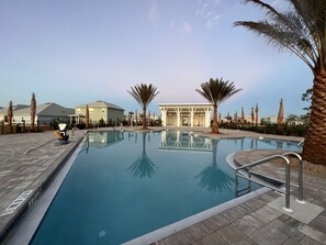 Piscina con vista despejada de los alrededores, incluyendo una estructura cubierta y palmeras.