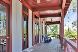 A covered porch with a ceiling fan, wooden railings, and a row of rocking chairs. - Captain Morgan | Steps to Beach | Community Pool | Boardwalk to Beach (WindMark Beach)