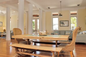 A spacious living area with a wooden table, woven chairs, and a sofa. - Captain Morgan | Steps to Beach | Community Pool | Boardwalk to Beach (WindMark Beach)