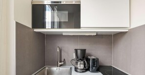 Een kleine keuken met een oven van roestvrij staal, een koffiezetapparaat en een broodrooster.