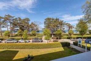 A parking area with cars, a signboard, and a view of the sea. - Beach Whispers (Sea View) (Binz)