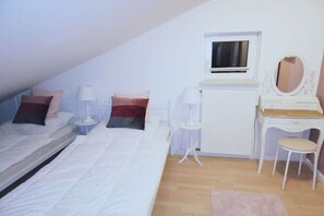 A bedroom with a bed, bedside tables, a dresser, a mirror, and a window. - Holiday home with 3 bedrooms (Rabenkirchen-Faulück)