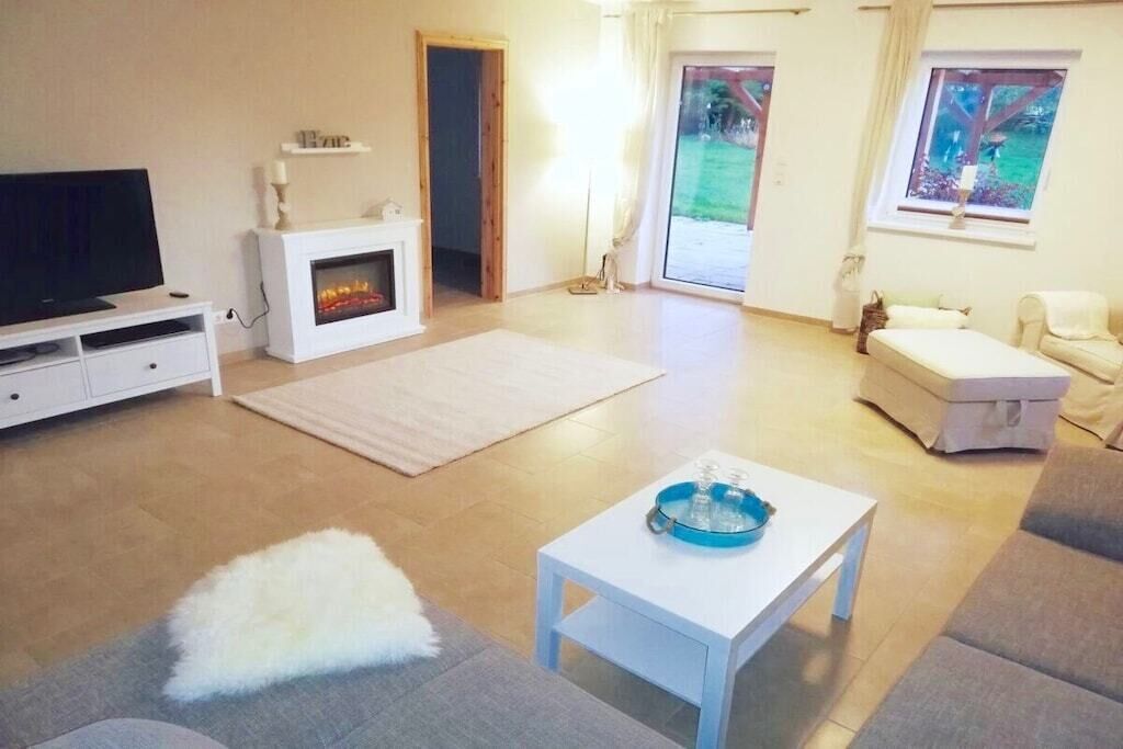 Un salon comprenant une télévision, une cheminée, un canapé et une petite table sur laquelle se trouve un bol.