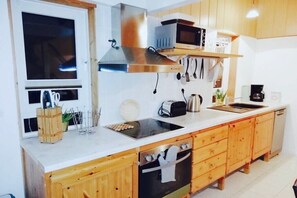 A modern kitchen with wooden cabinets, stainless steel appliances, and a window. - Holiday home with 3 bedrooms (Rabenkirchen-Faulück)