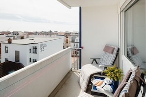 Ein Balkon mit Blick auf die Stadt, ein Stuhl, ein kleiner Tisch mit Tablett und ein Gebäude mit der Aufschrift 'FERIEN DOMIZIL 25'.