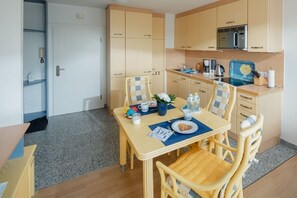 Une cuisine compacte dotée de meubles en bois, d’un four à micro-ondes et d’un coin repas avec une table et des chaises.