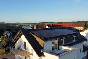 Ein Wohngebäude mit Schrägdach, Solaranlage und Balkon.
