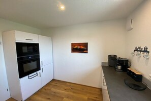 Uma cozinha compacta com forno embutido, espaço para café e pequena área de refeições.
