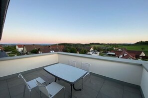 Eine Dachterrasse mit Tisch und Stühlen mit Blick auf eine Wohngegend.