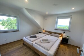 Ein Schlafzimmer mit einem großen Bett, zwei Nachttischen und zwei Fenstern.