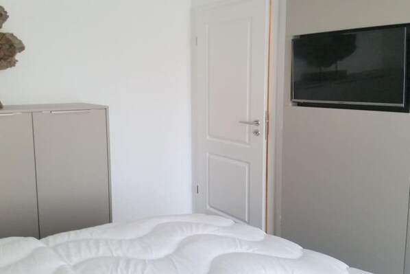 Ein Schlafzimmer mit einem Bett, einem Kleiderschrank und einem Fernseher an der Wand.