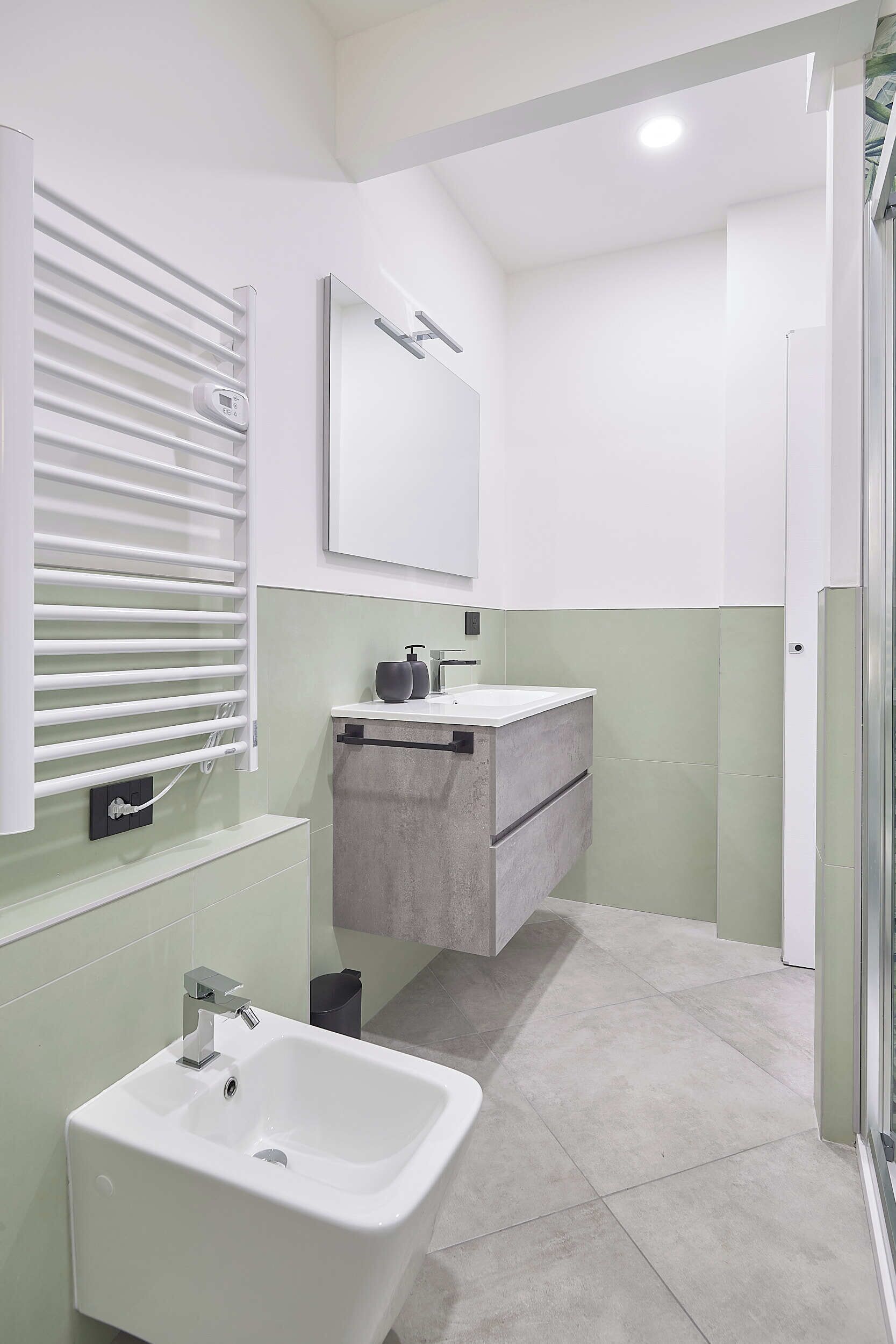 Een moderne badkamer met een wit wastafelmeubel, een spiegel en een handdoekrek.