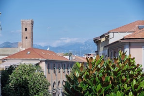 A building with a tower, surrounded by other structures and greenery. - Casa Maggie (Albenga)