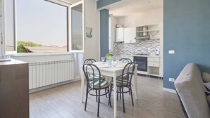 Una cocina moderna con armarios blancos, salpicadero de azulejos y un comedor con mesa y sillas.
