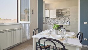 Un comedor con una mesa dispuesta para dos, una planta en maceta y vistas de la cocina.