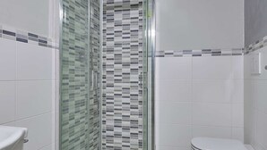 Un baño con ducha de mampara de vidrio, inodoro y bidé.