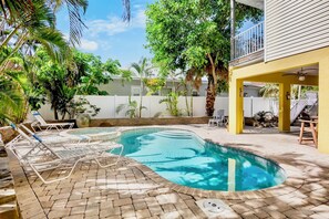 Ein Swimmingpool mit Liegestühlen und einer überdachten Terrasse.