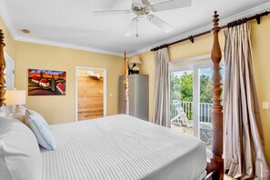 Ein Schlafzimmer mit Bett, Deckenventilator, Gemälde, Kleiderschrank und Blick ins Freie.