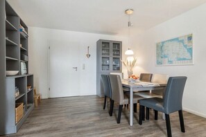A dining area with a table, chairs, a cabinet, and a map on the wall. - Holiday apartment with 1 bedroom (Fehmarn)