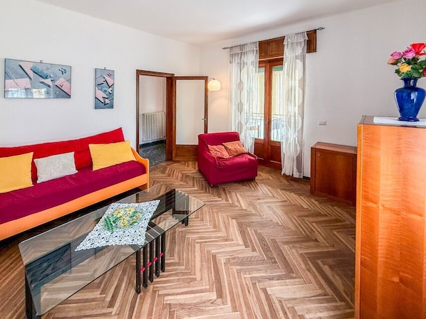 A living room with a red sofa, a glass coffee table, and a red armchair. - 5 Minutes from La Godorta (Gozzano)