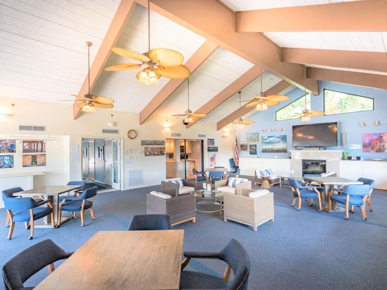 A spacious indoor area with ceiling fans, a TV, and seating arrangements.