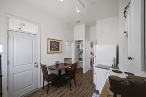 A compact kitchen with a dining table, chairs, a refrigerator, and a white door.