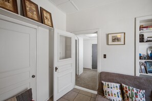 A hallway with a white door, a mirror, and a shelf with books and decorative items.