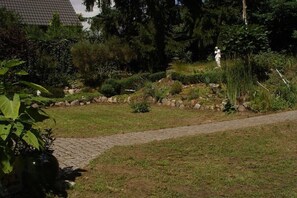 Ein Garten mit einem gepflasterten Weg, verschiedenen Pflanzen und einer Statue.