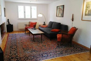 Ein Wohnzimmer mit einer Couch, einem Sessel, einem Couchtisch und einem gemusterten Teppich.