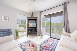 Ein modernes Wohnzimmer mit einer Couch, einem Couchtisch, einem Bücherregal und einer großen Glasschiebetür, die auf einen Balkon führt.