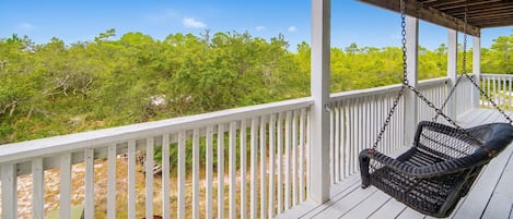 A wooden deck with white railings and a hanging chair.