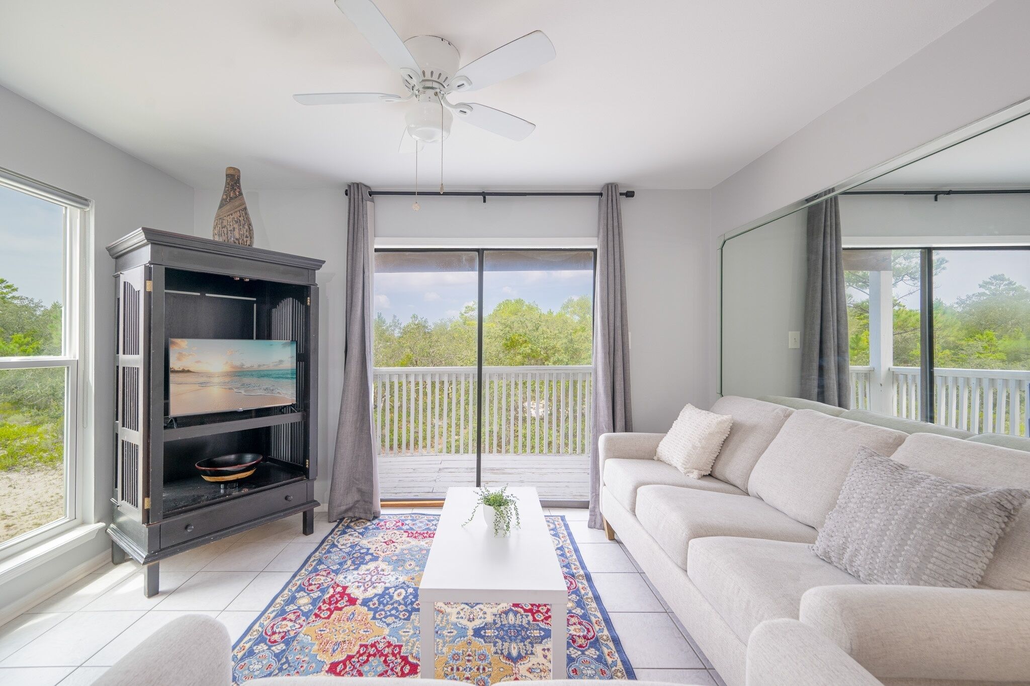 A living room with a TV, sofa, coffee table, and a balcony with a view.
